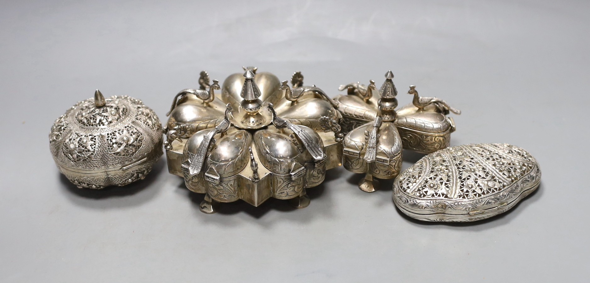 Two 20th century Indian white metal segmental spice boxes, decorated with peacocks, largest 13.5cm and two similar pierced scent boxes with covers.